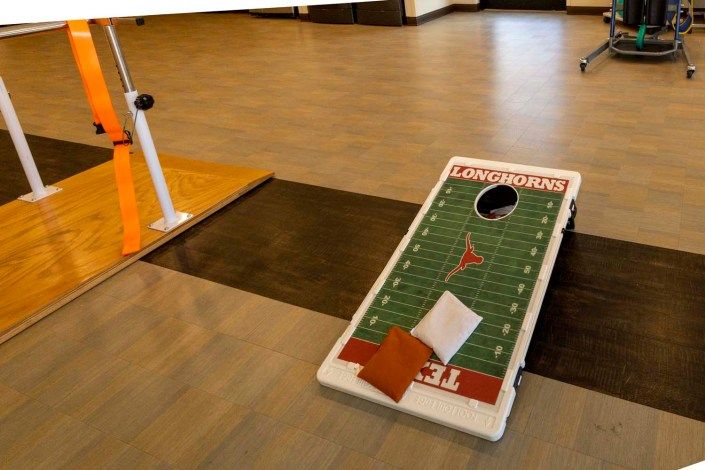 A football-themed cornhole board with bean bags indoors.