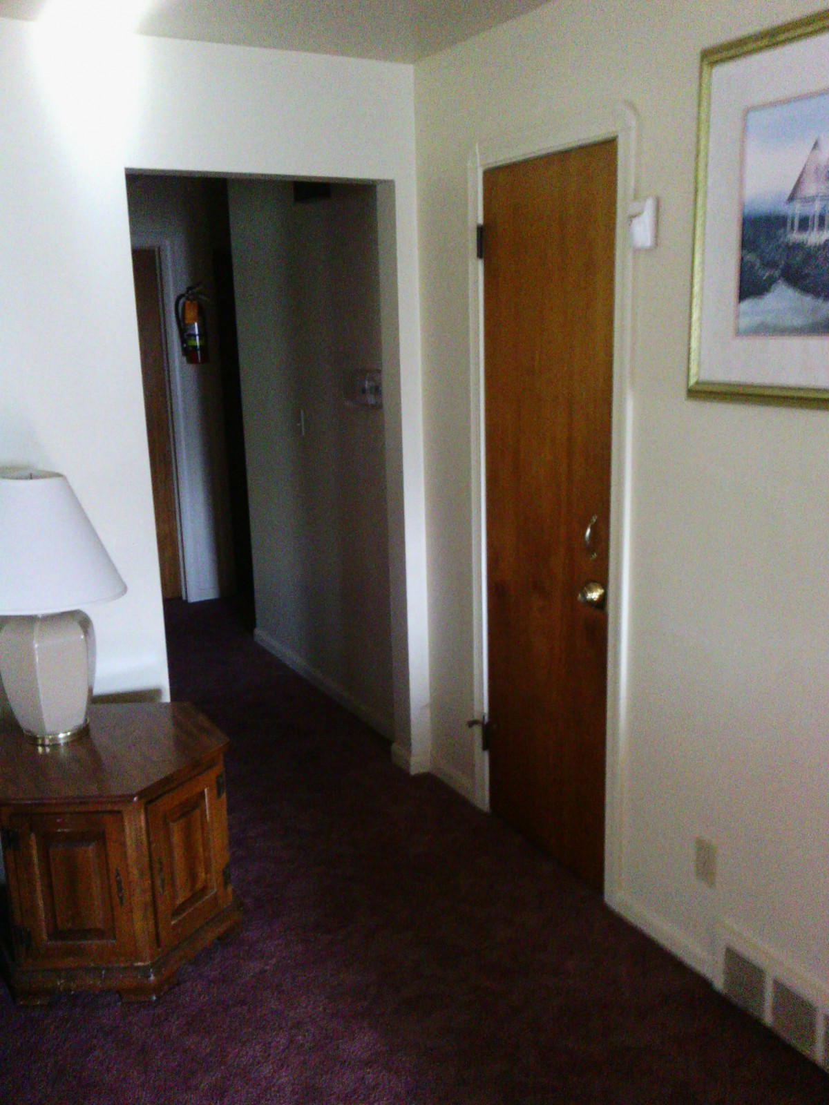 A cozy hallway with a wooden door, side table, and decorative painting.