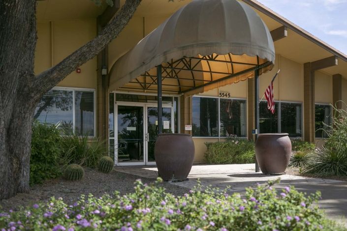 A building entrance with an awning and landscaped surroundings.