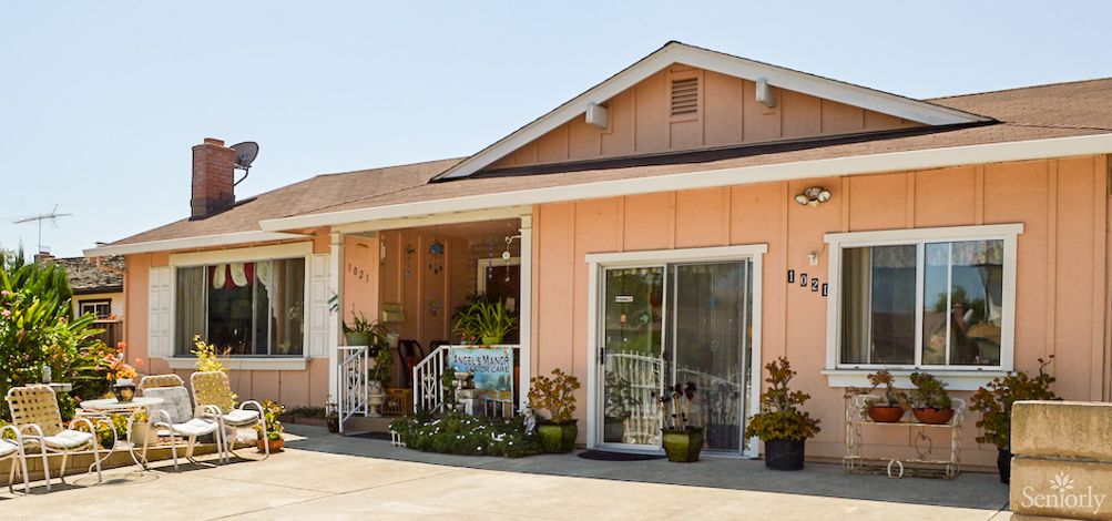 A quaint house with a porch and potted plants in the front yard.