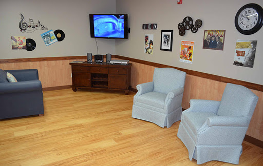 A cozy living room setup featuring two blue chairs, a television, and decorative wall art.