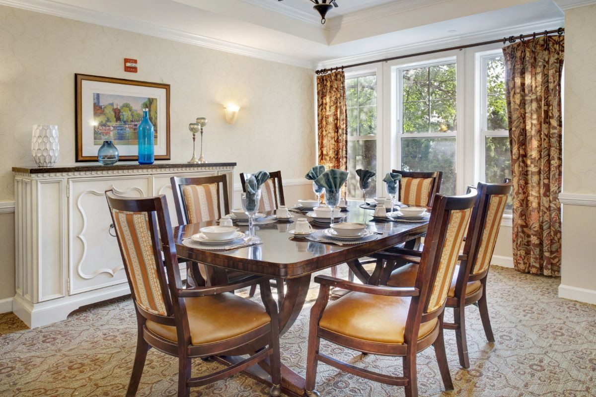 A well-furnished dining room with a large table and elegant chairs, featuring natural light from the windows and tasteful decorations.