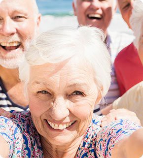 A group of senior friends smiling happily outdoors.