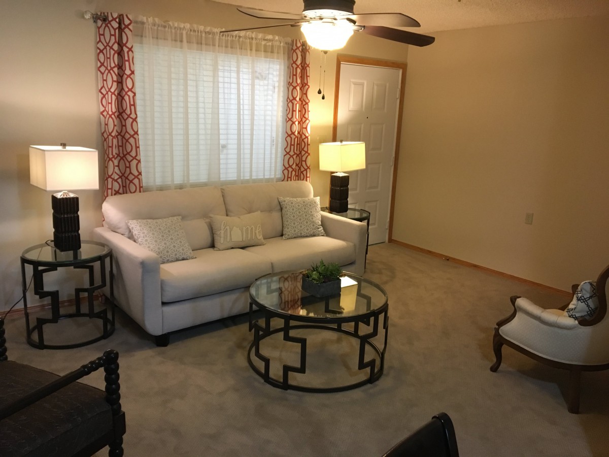 A cozy living room with a white sofa, glass coffee table, and stylish lamps.