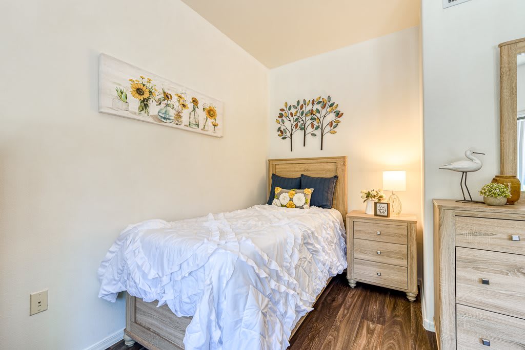 A cozy bedroom with a single bed, decorative pillows, and wall art.