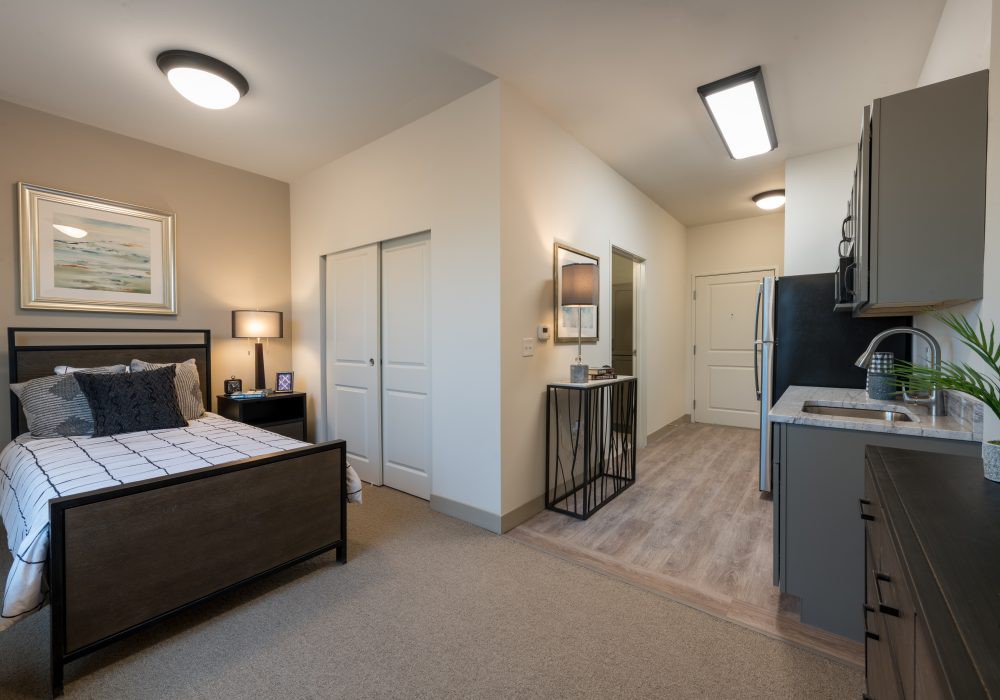 A modern studio apartment featuring a cozy bedroom area and a compact kitchen with minimalist decor.