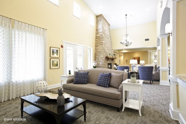 A spacious and well-lit living room featuring comfortable seating, a fireplace, and elegant decor.