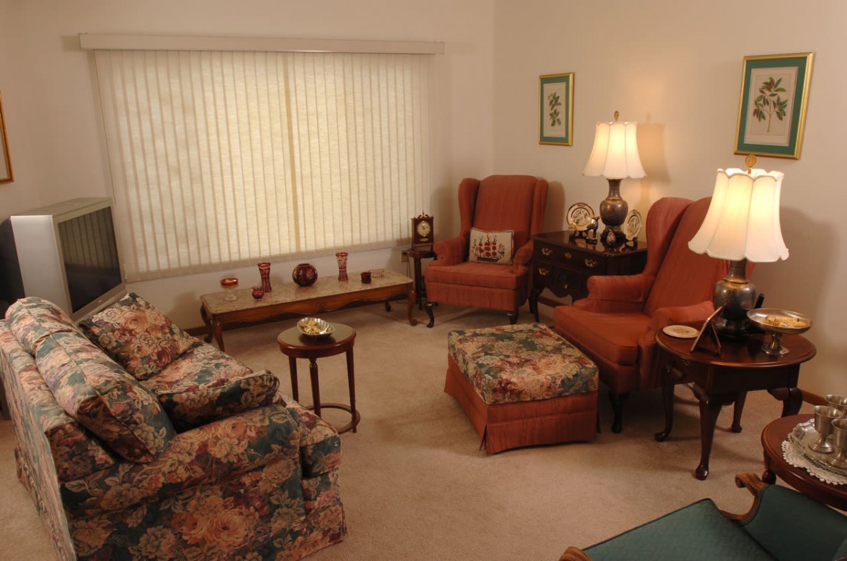 A cozy living room with patterned armchairs, a lamp, and a coffee table.