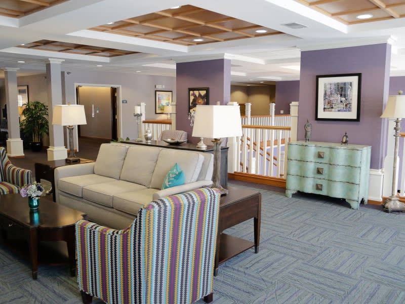 A cozy living room interior with a sofa, striped chairs, and table lamps.
