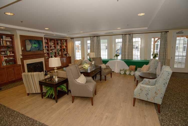A cozy living room with comfortable armchairs, a fireplace, and a well-organized bookshelf.