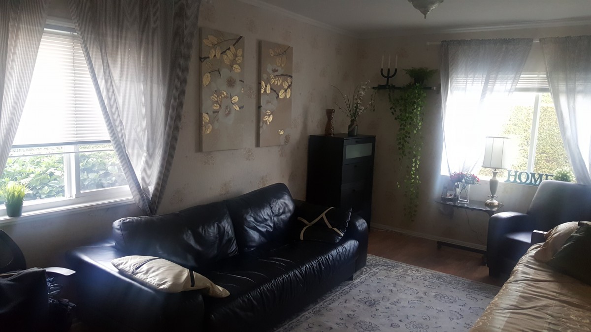 A cozy living room with a black leather sofa, wall art, and soft lighting.