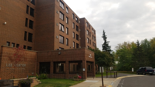 A multi-story residential building with a brick facade under a cloudy sky.