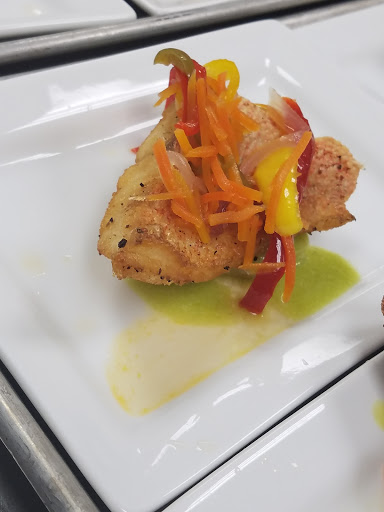 A beautifully plated seafood dish topped with colorful sauted vegetables.