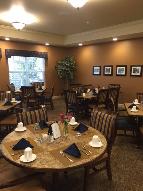 A cozy dining room with neatly set tables and warm lighting.