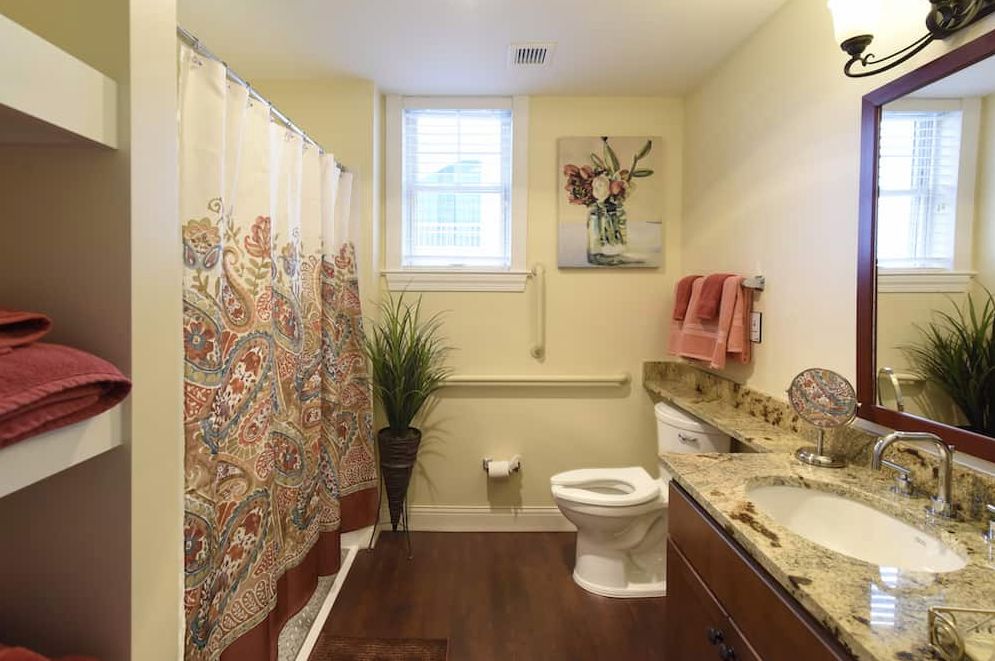 A well-lit bathroom with a colorful shower curtain and decorative elements.