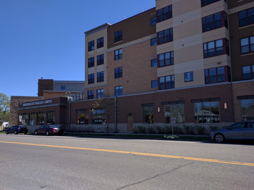 A modern multi-story building viewed from the street, showcasing its architecture and surrounding vehicles.