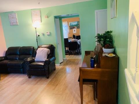 A cozy living room with green walls, featuring comfortable seating and a piano.