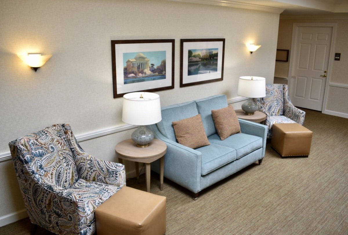 A cozy living room with a light blue sofa, patterned chairs, and decorative paintings on the wall.