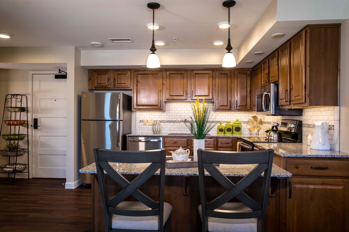 A modern kitchen with wooden cabinets, stainless steel appliances, and stylish pendant lighting.