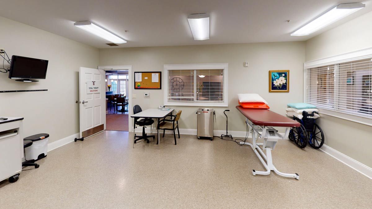 A clean and organized examination room in a clinic, featuring a medical table and desk.