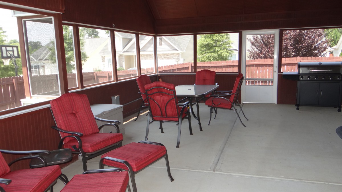 A screened patio with red-cushioned chairs and a table, offering an inviting outdoor seating area.