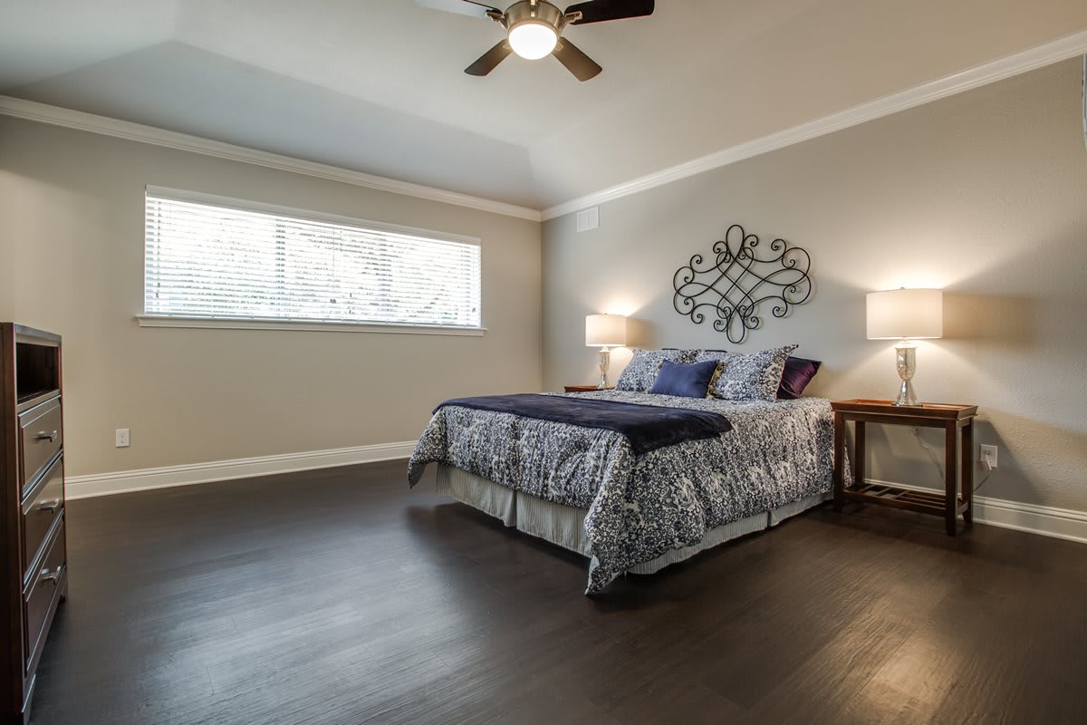 A cozy bedroom with a stylish bed, wooden flooring, and wall art.