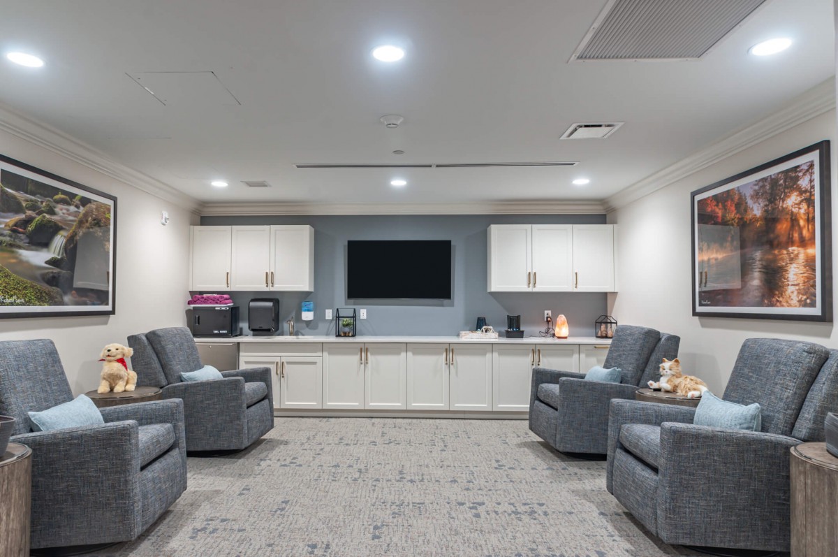 A modern waiting room with comfortable recliners and a central television.