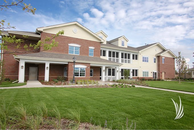 A large residential building with a well-maintained lawn and a clear blue sky.