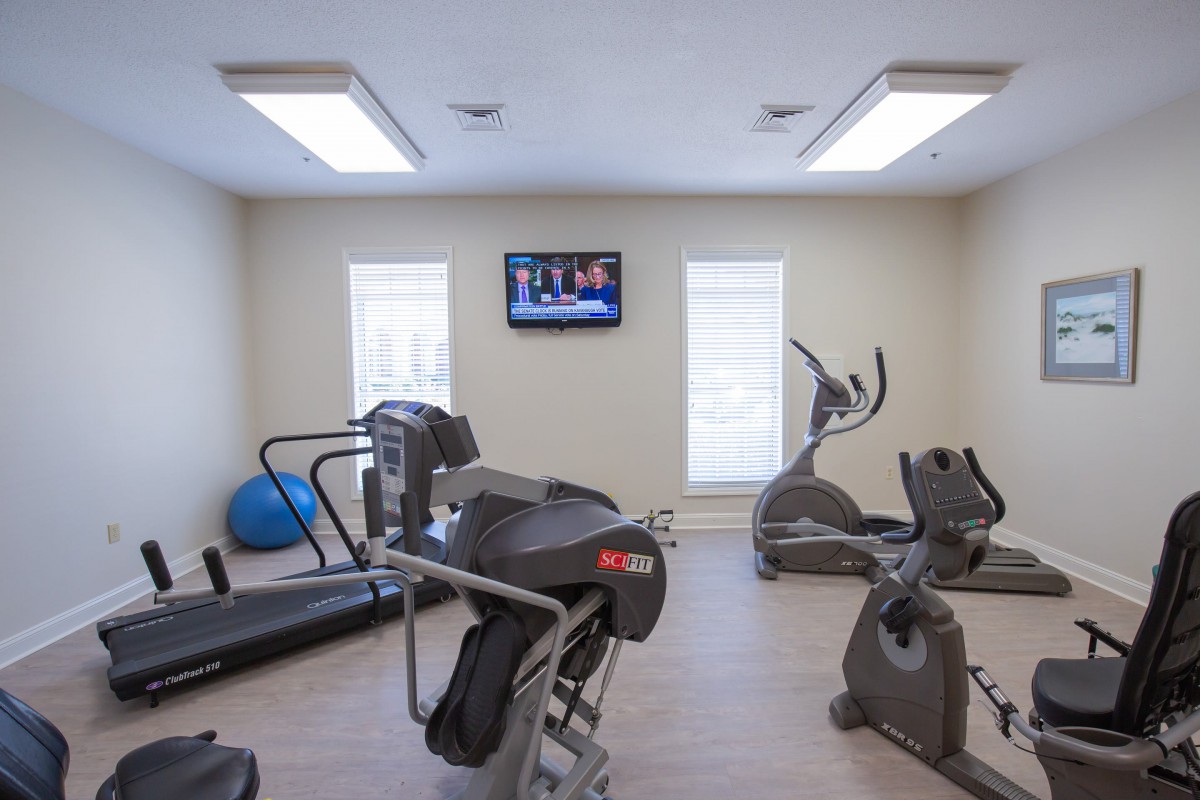 A modern gym with various exercise equipment including treadmills and stationary bikes.