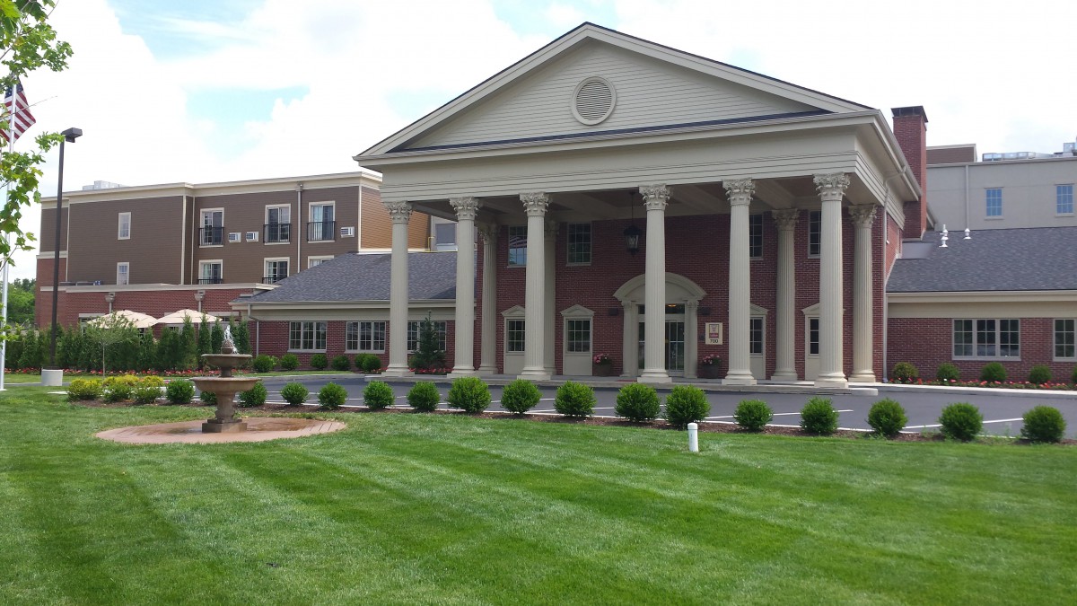 A classical-style brick building with columns and a well-maintained lawn.