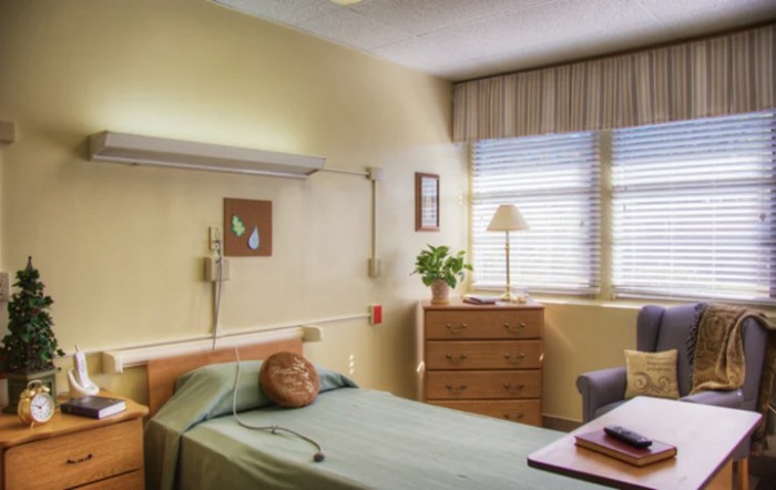 A hospital room with a bed, medical equipment, and a window with blinds.