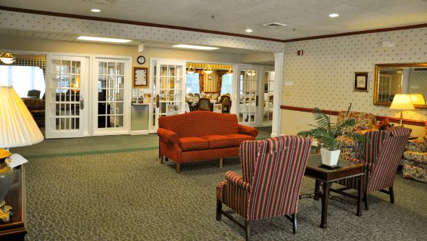 A cozy lobby area featuring a red sofa and striped armchair with a plant nearby.