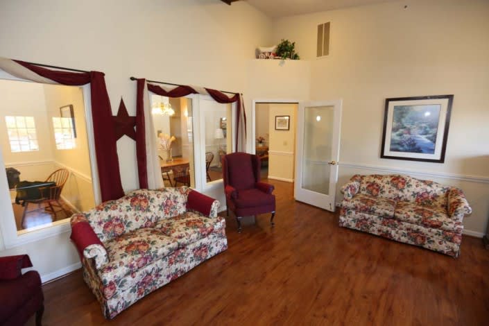 A cozy living room with floral upholstered furniture and wood flooring.