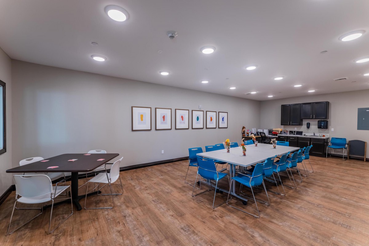 A modern conference room with blue chairs, long tables, and framed artwork on the wall.