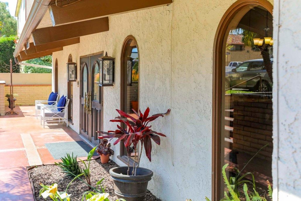 A charming building exterior featuring arched windows and lush potted plants.
