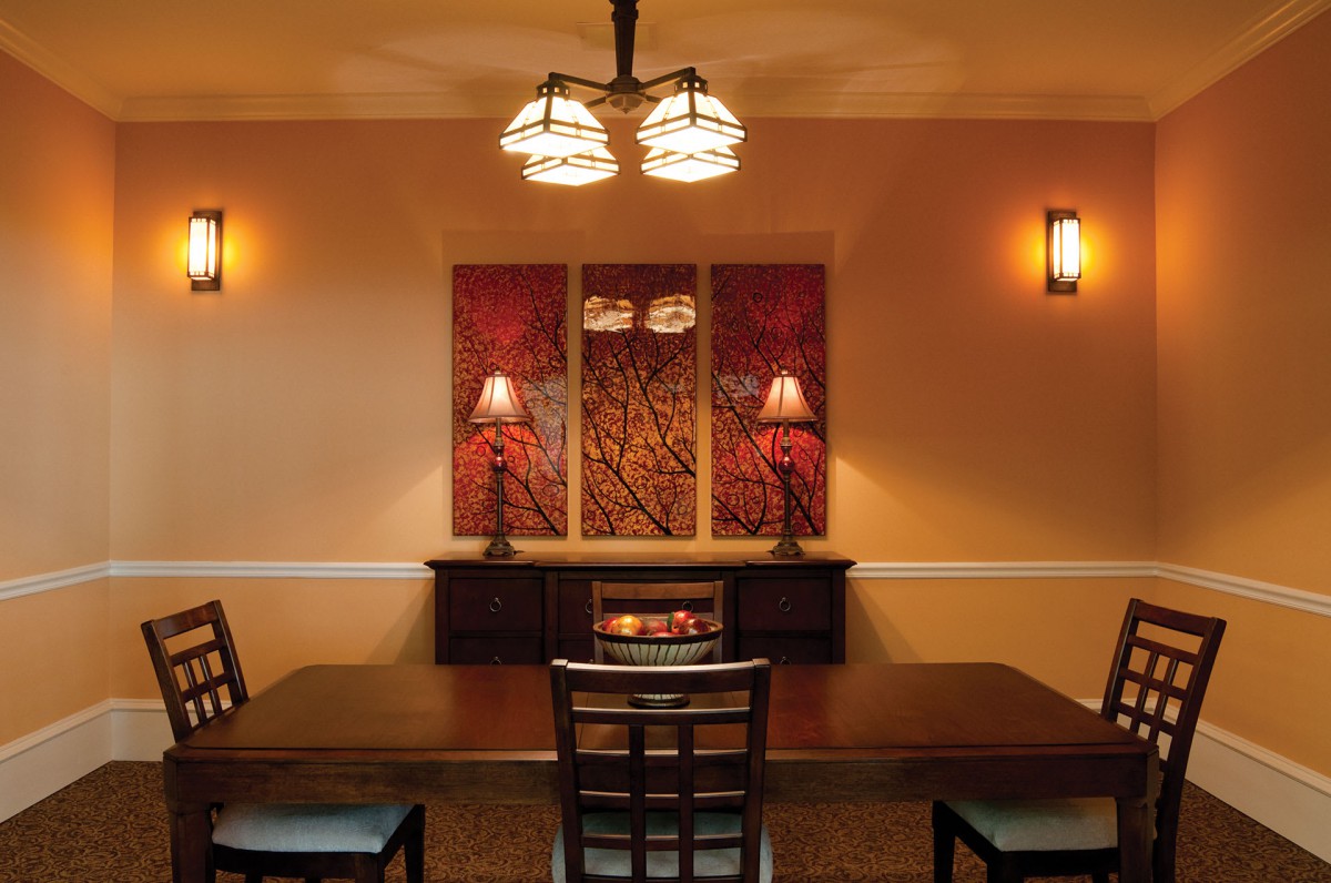 A cozy dining room with modern lighting and warm-toned artwork.
