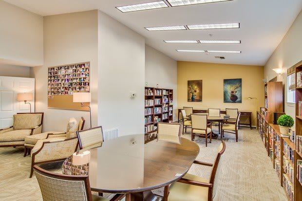 A cozy library reading area with tables, chairs, and bookshelves.