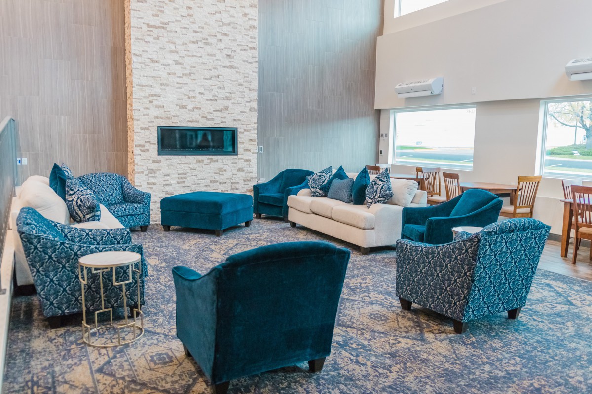 A modern living room with blue chairs, a white sofa, and a fireplace.