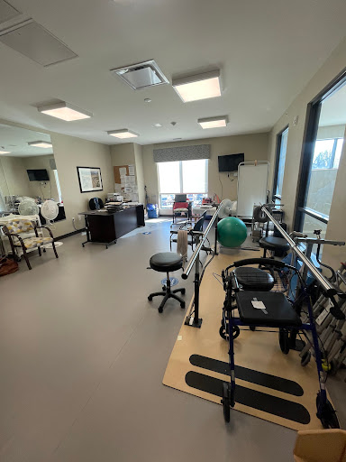 A spacious rehabilitation therapy room equipped with exercise equipment and natural lighting.