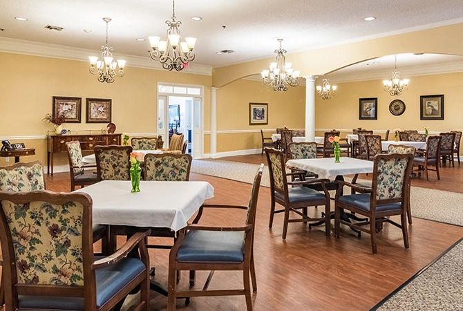 An elegant dining room with multiple tables set under chandeliers.