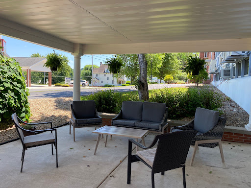 A cozy outdoor seating area with comfortable chairs and a table, surrounded by greenery.