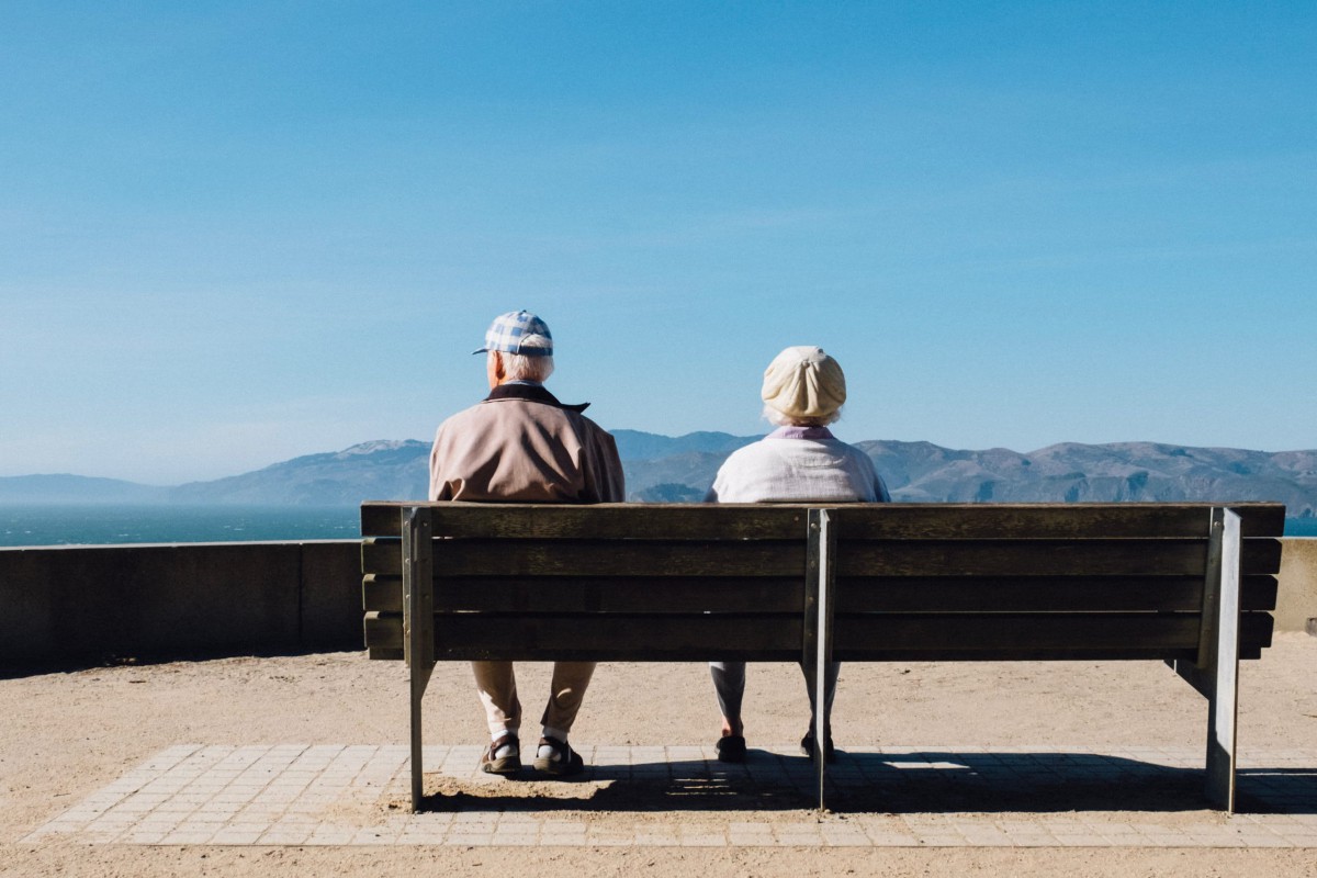 An elderly couple enjoys a peaceful moment by the seaside on a sunny day.
