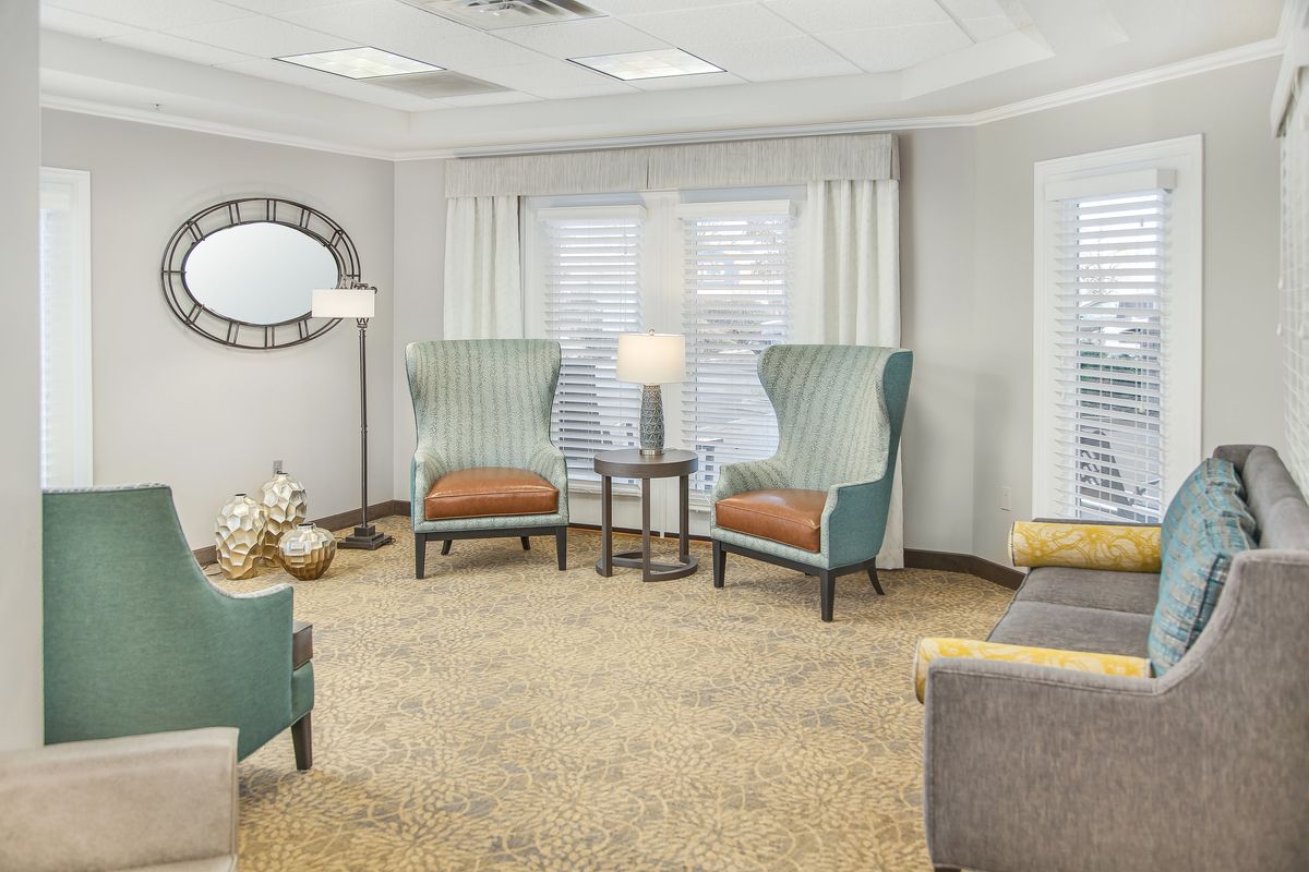 A cozy living room with wingback chairs, a small round table, and modern decor.