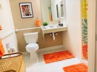 A modern bathroom with bright orange accents and clean white fixtures.