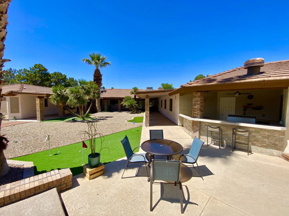 A sunny courtyard with outdoor seating and lush palm trees.