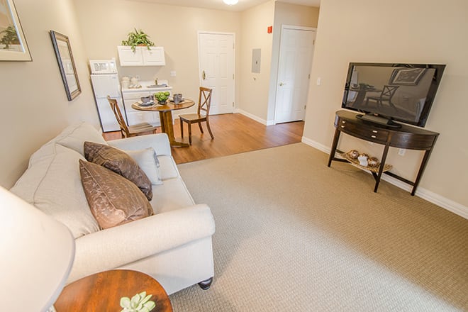 A cozy living room with a sofa, television, and adjacent dining area.