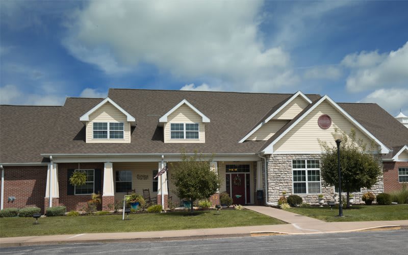 A modern suburban house with a well-maintained yard and a cloudy sky backdrop.