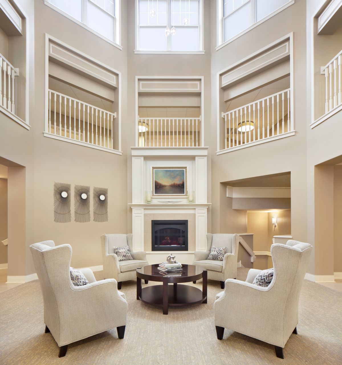 Elegant living room with armchairs surrounding a central fireplace and an open balcony design.