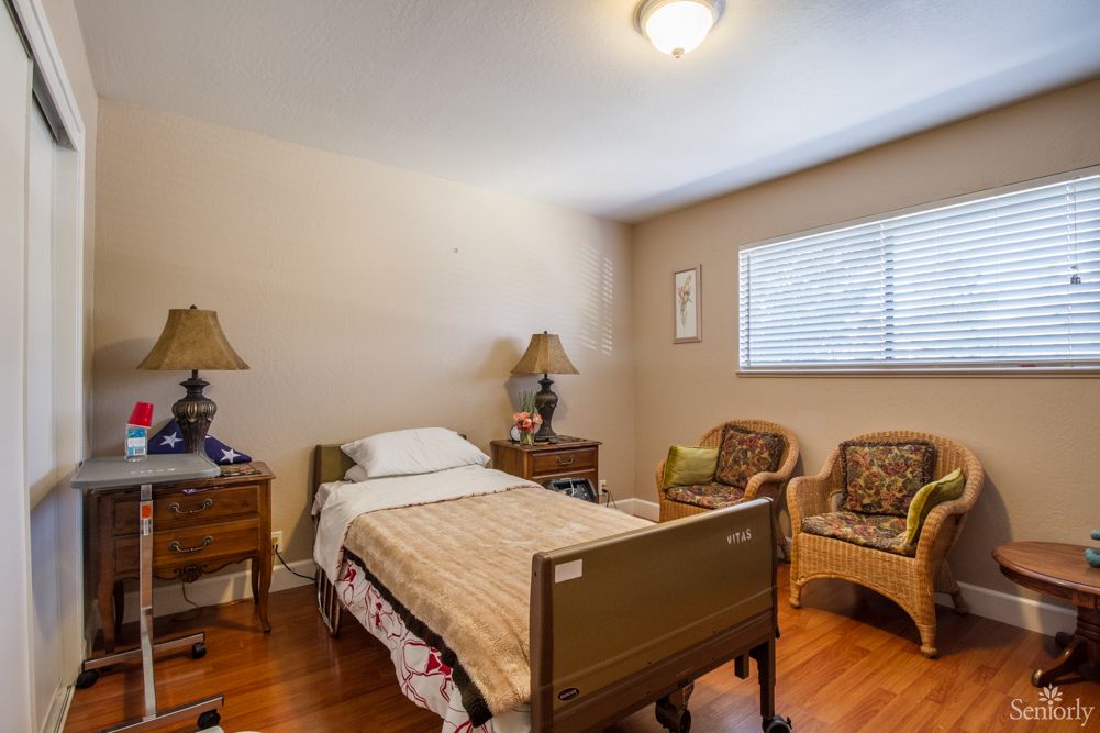 A cozy bedroom with a single bed, nightstands with lamps, armchairs, and a window.