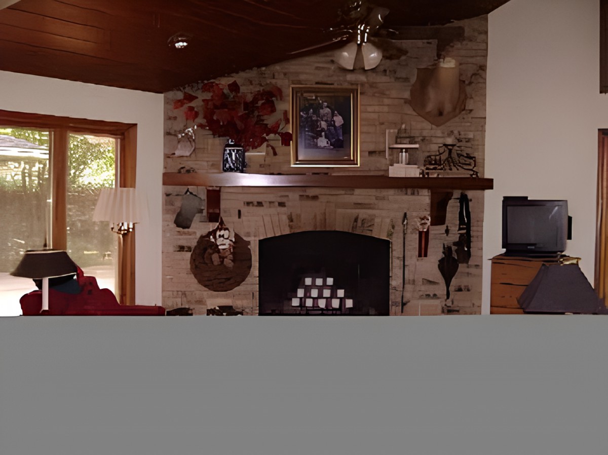 A cozy living room with a brick fireplace and various decorations on the mantel.